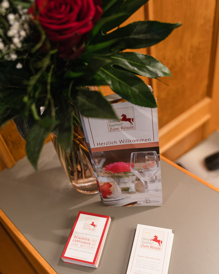 Rezeption mit frischen Blumen und Informationsmaterial im Hotel Gasthof Zum Rössle Altenstadt